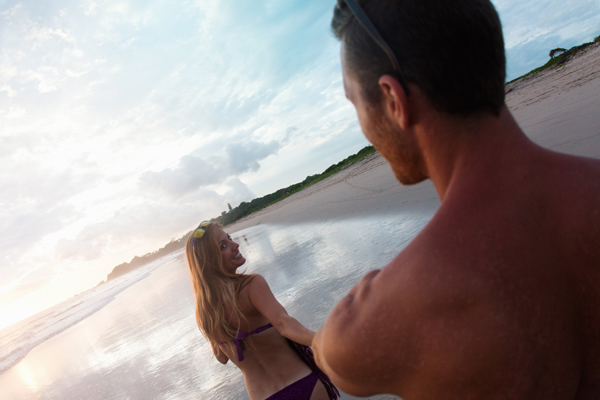 12 Jul 2014, Costa Rica --- Over shoulder view of mid adult woman leading boyfriend by hand on beach, Nosara, Guanacaste, Costa Rica --- Image by © Yew! Images/Image Source/Corbis